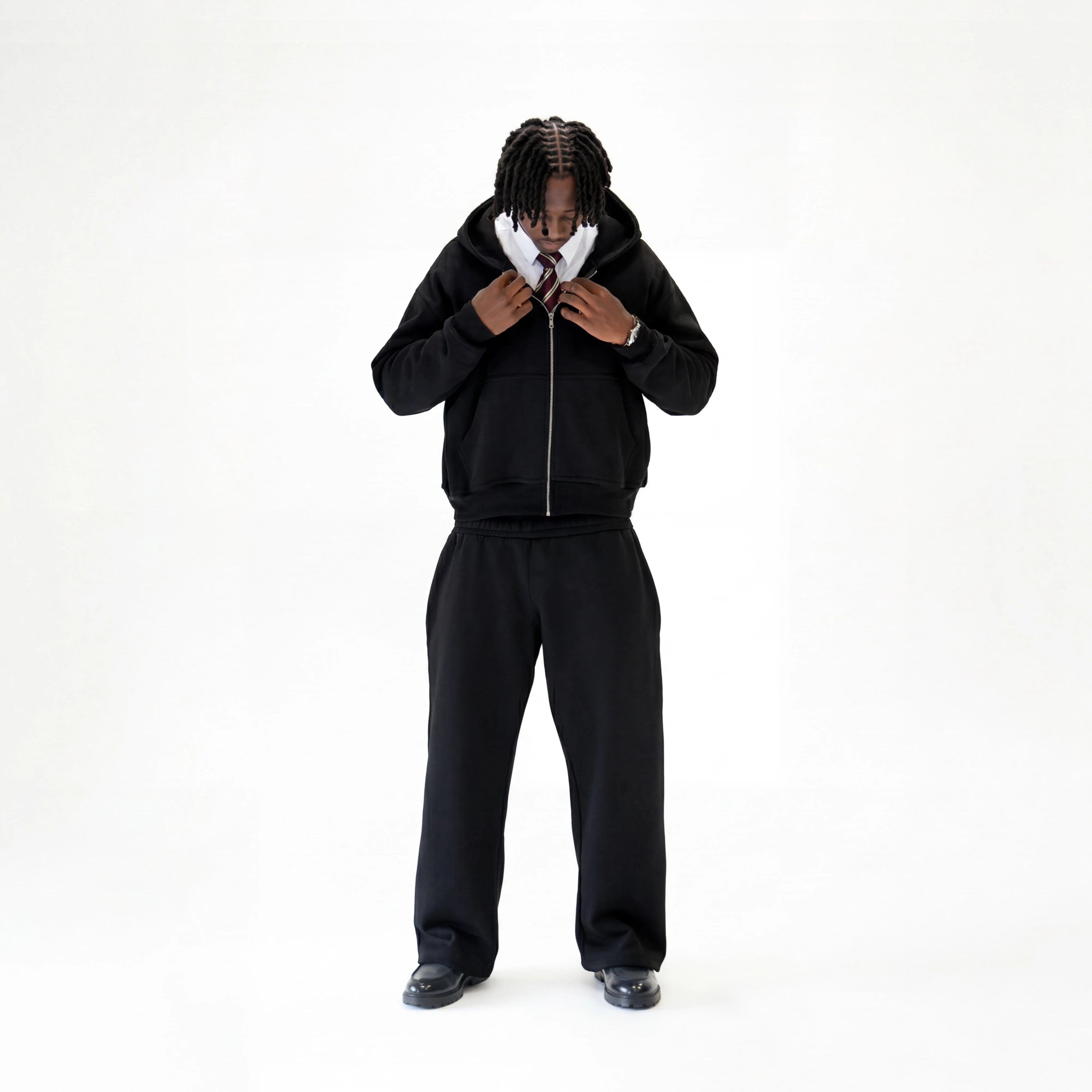 Model wearing premium black tracksuit on a white studio background.